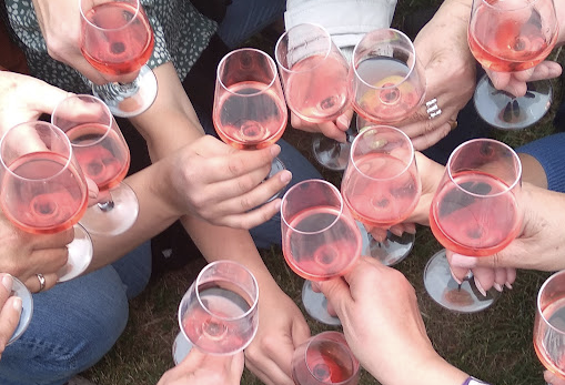 Gäste stoßen mit Rosé an – Blick auf die Gläser von oben